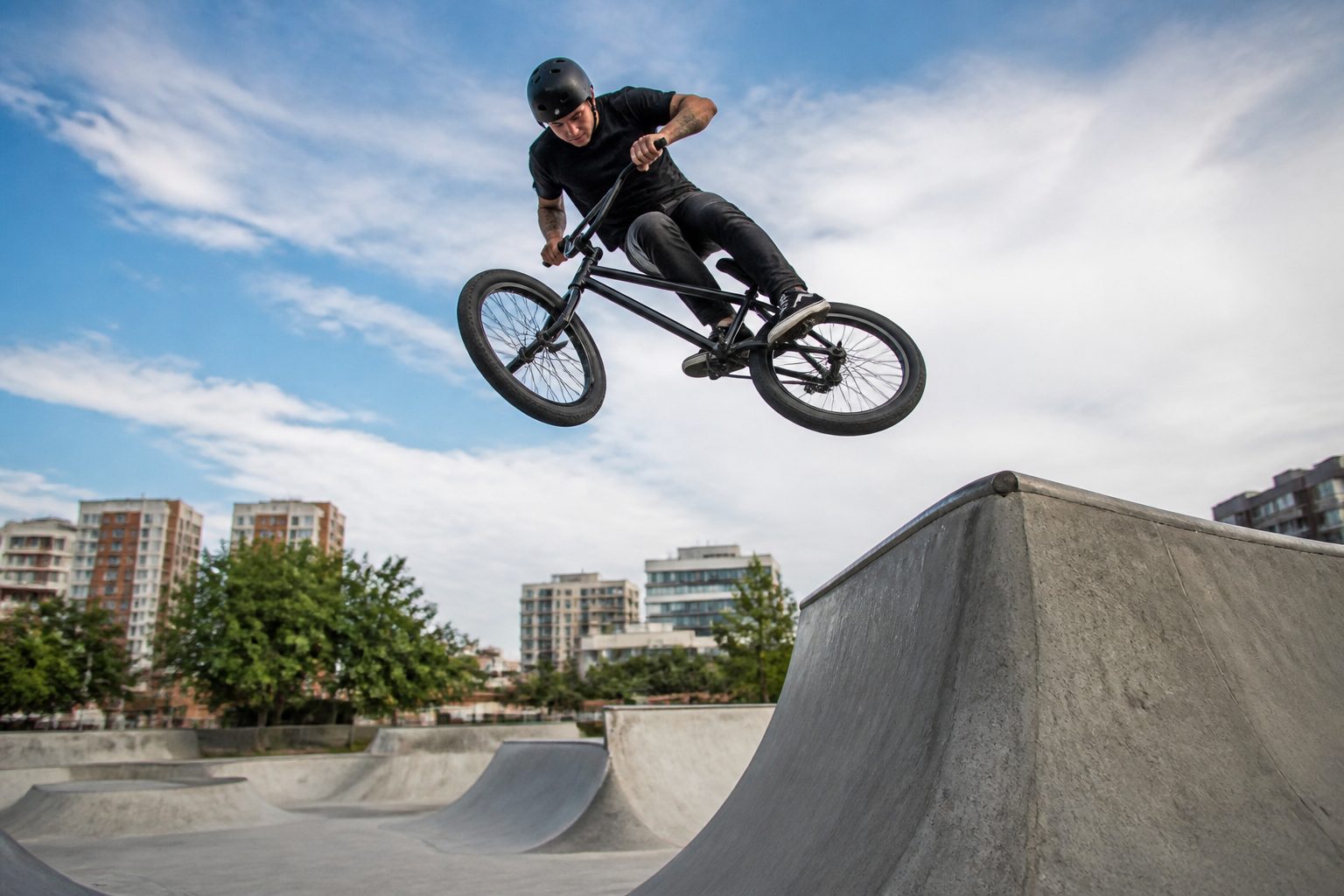 rider bmx freestyle réalisant un saut au-dessus d'une rampe de skatepark
